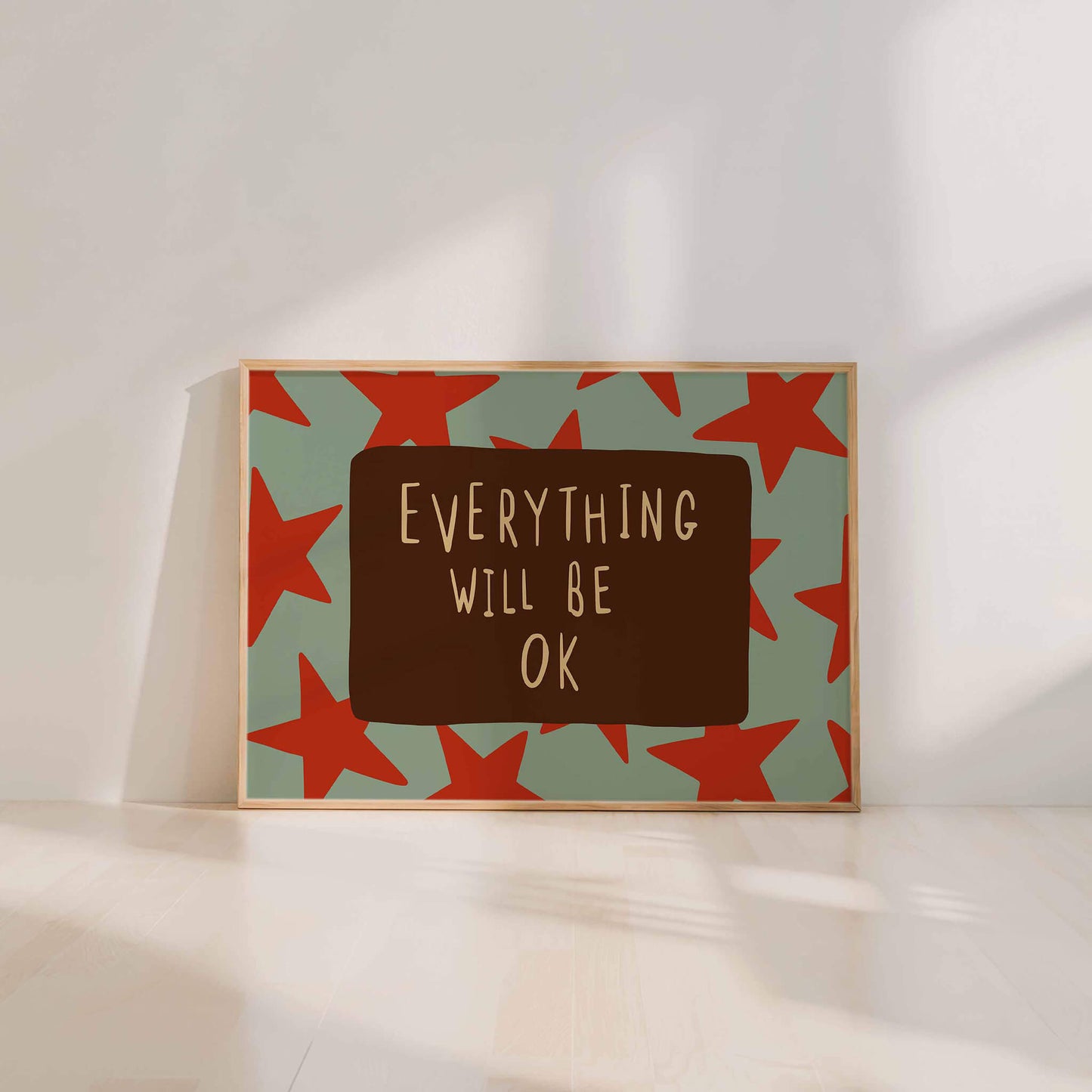 a framed poster with a green background and red stars, displaying the text "Everything will be OK" in a brown rectangle.