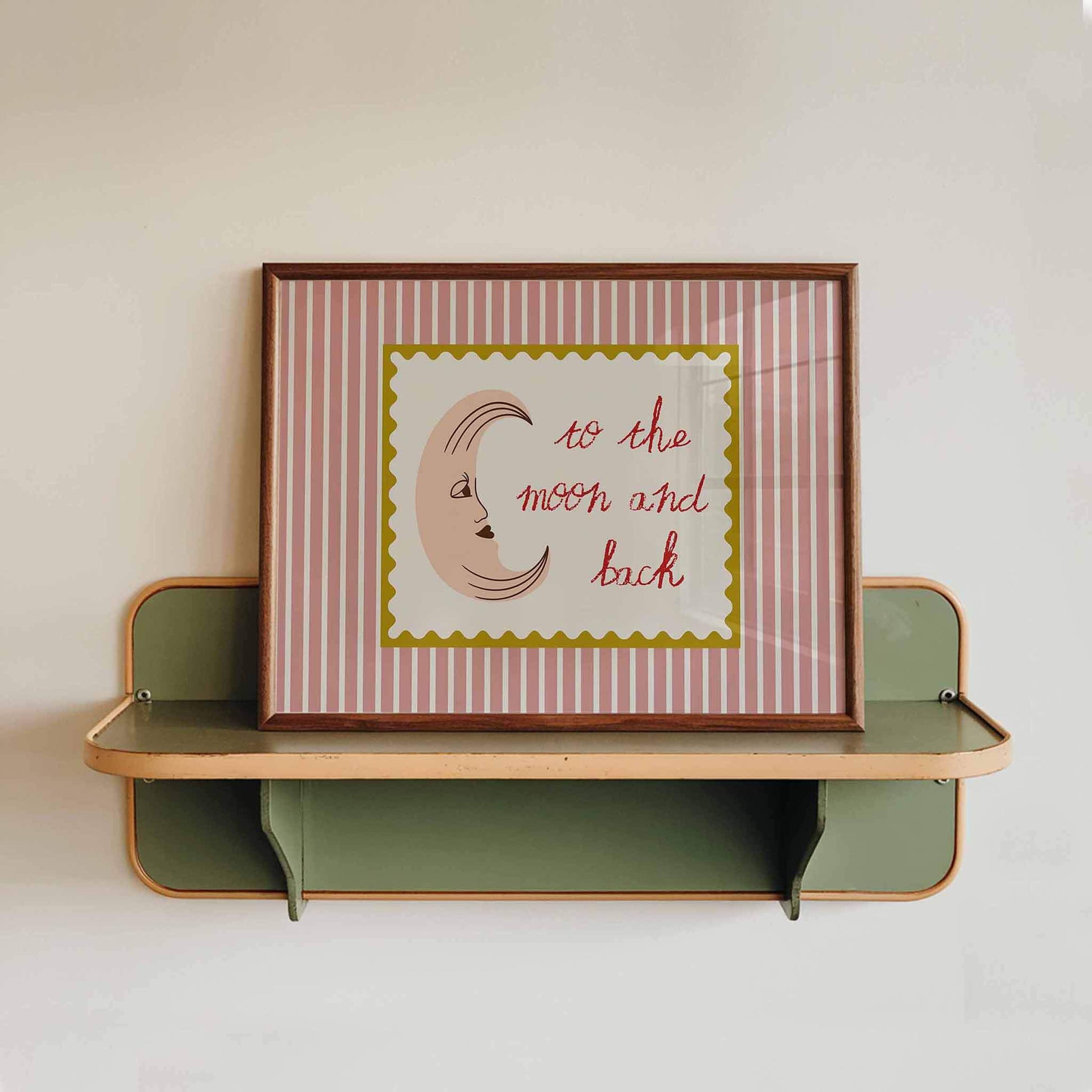 Framed artwork with 'to the moon and back' text on a striped background, displayed on a wall shelf.