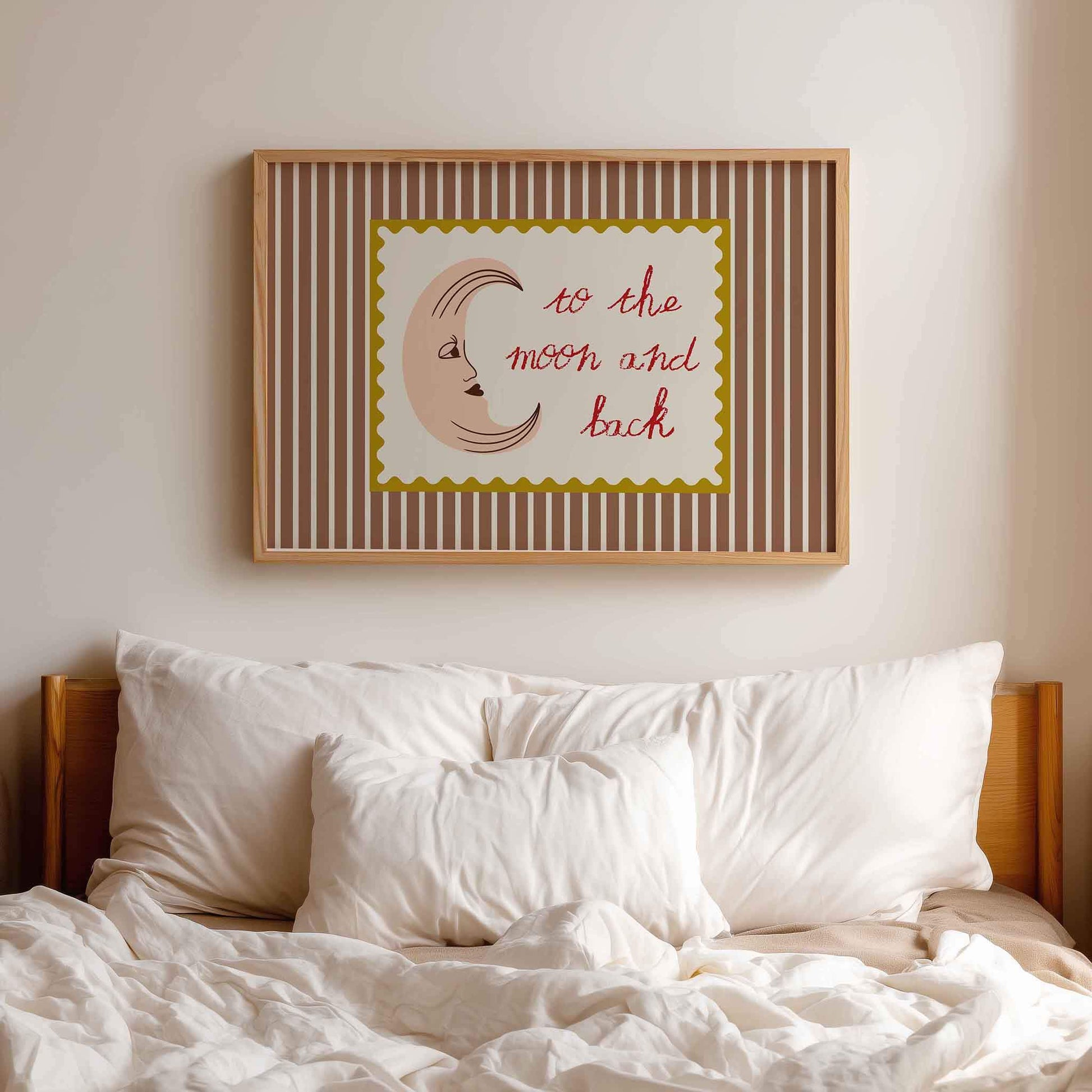 Framed artwork with 'to the moon and back' text above a bed with white pillows and bedding.