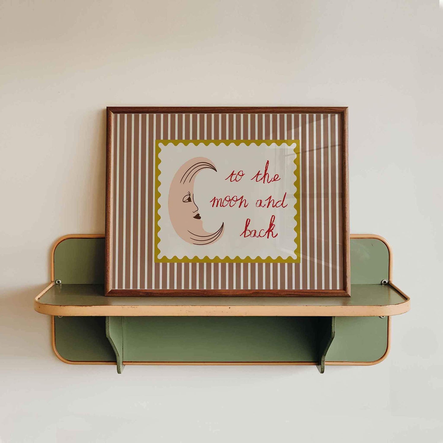 Framed artwork with 'to the moon and back' text on a striped background, displayed on a wall shelf.