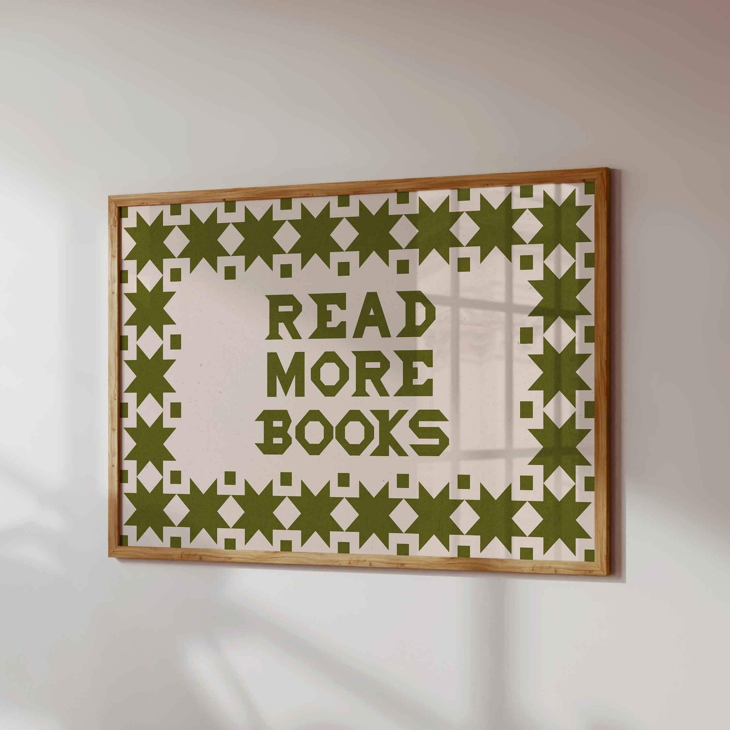 Framed artwork with 'Read More Books' text and geometric pattern on a white wall.