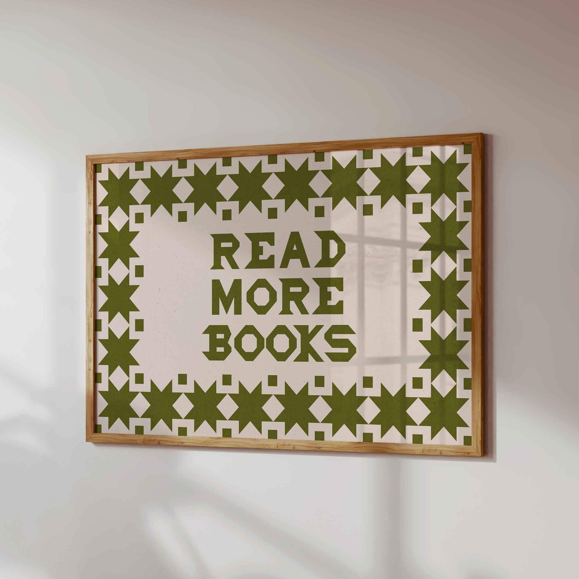 Framed artwork with 'Read More Books' text and geometric pattern on a white wall.