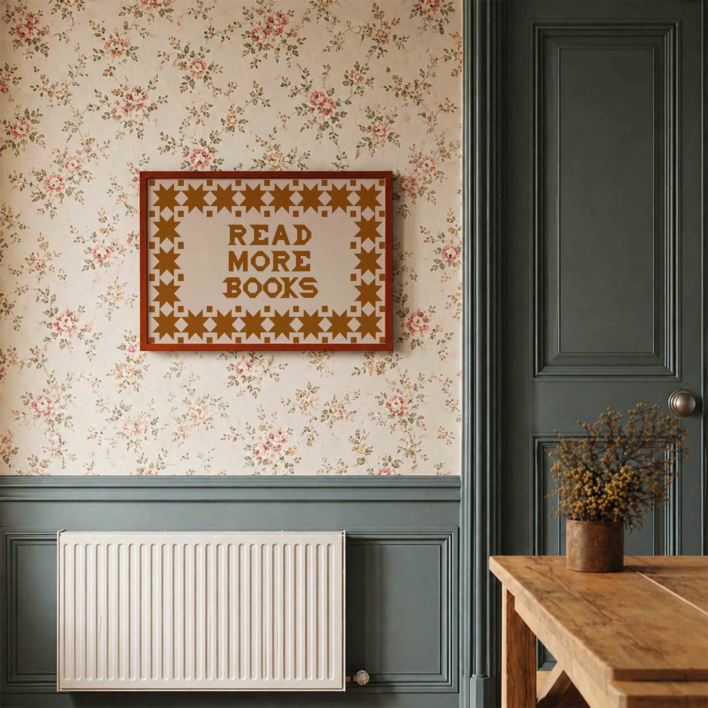 Decorative wall with floral wallpaper, framed quote, radiator, and wooden table.
