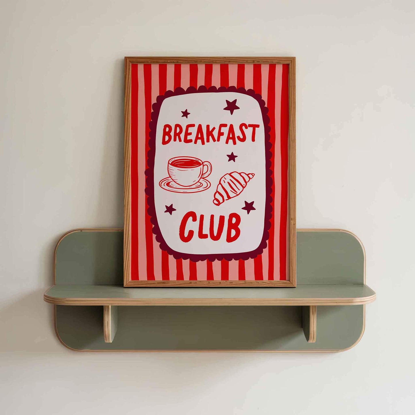 a framed sign with the text "BREAKFAST CLUB" and illustrations of a cup of coffee and a pastry.