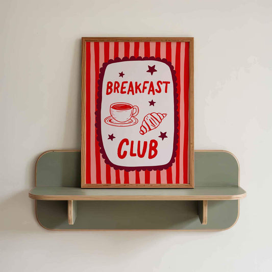 a framed sign with the text "BREAKFAST CLUB" and illustrations of a cup of coffee and a pastry.