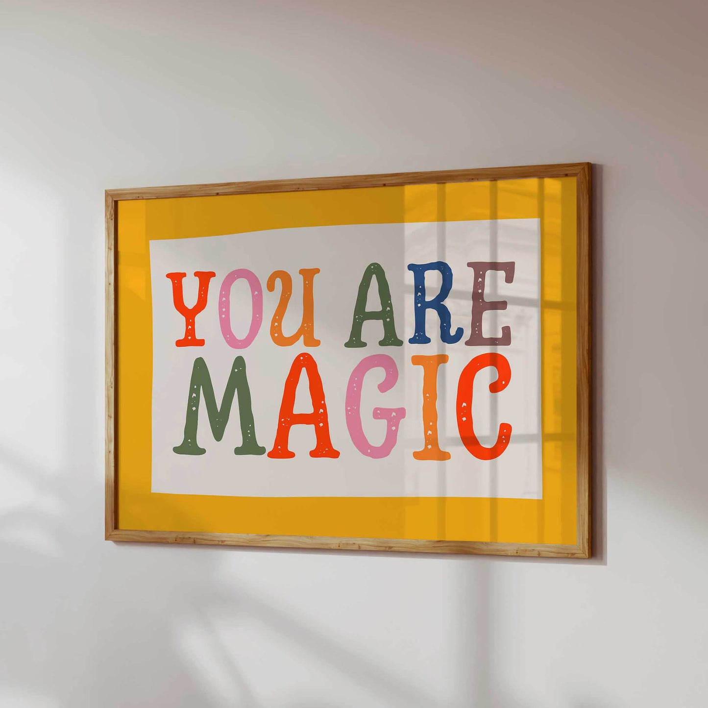 a framed poster with the text "YOU ARE MAGIC" in a vibrant, colorful font.
