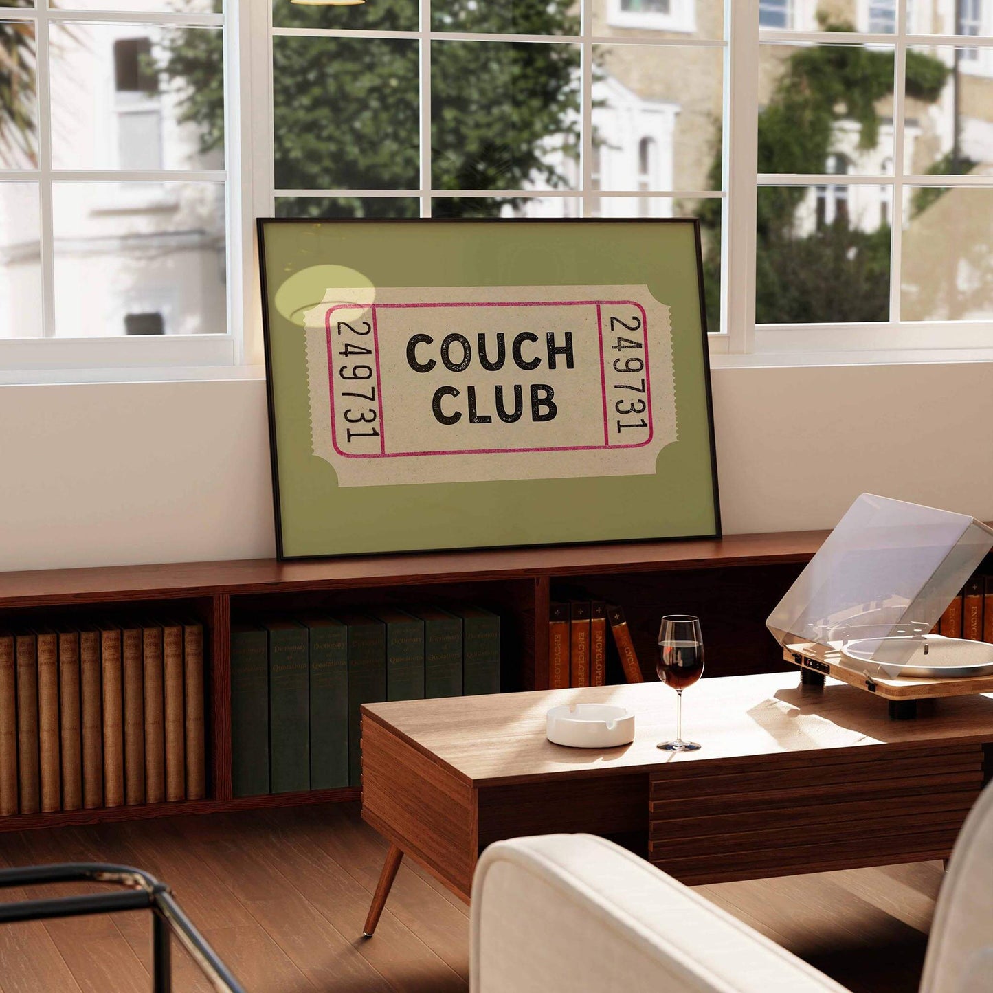 a framed poster of a ticket for the "Couch Club" displayed on a shelf in a living room.