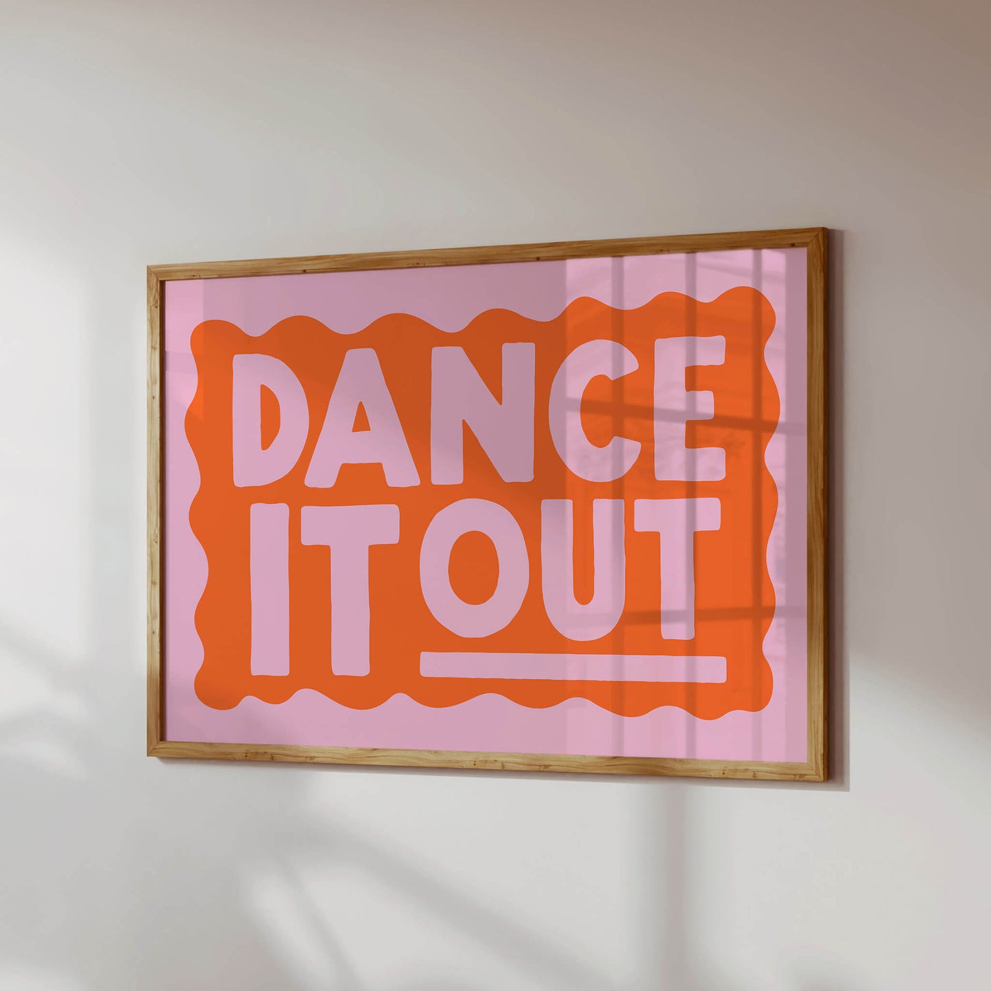 a framed poster with the text "DANCE IT OUT" in a bold, orange and pink color scheme.