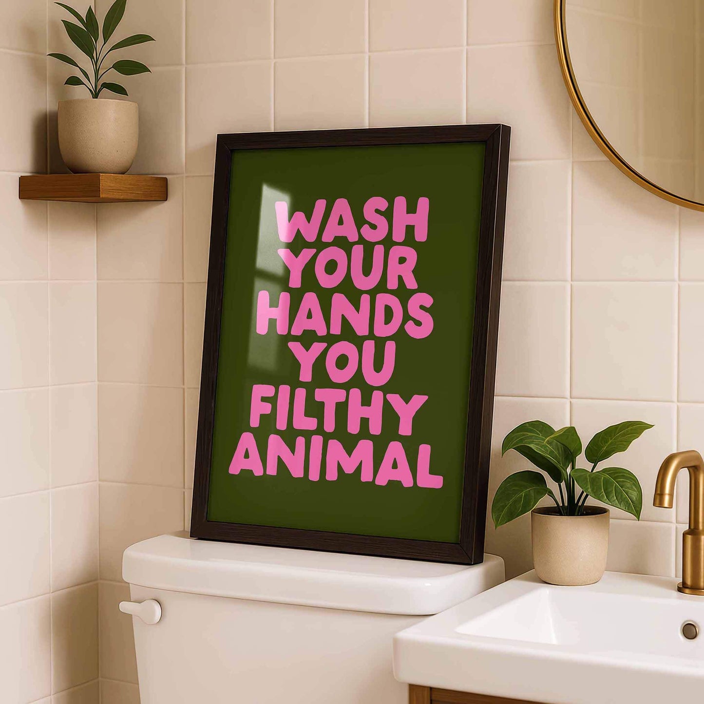 a framed poster with the text "WASH YOUR HANDS YOU FILthy ANIMAL" displayed on a bathroom wall.