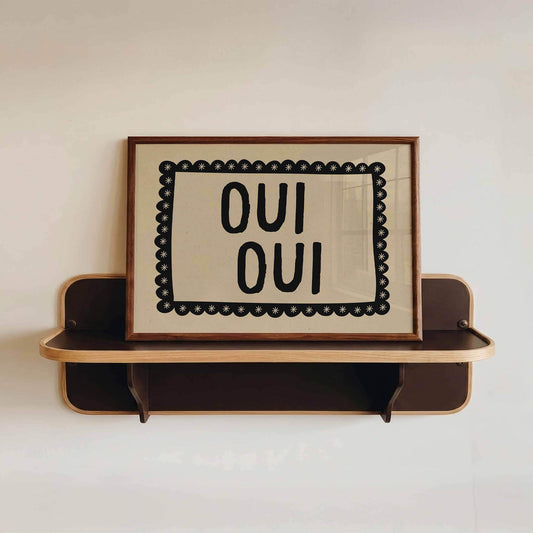 Wooden shelf with a framed sign reading 'OUI OUI' on a white wall.
