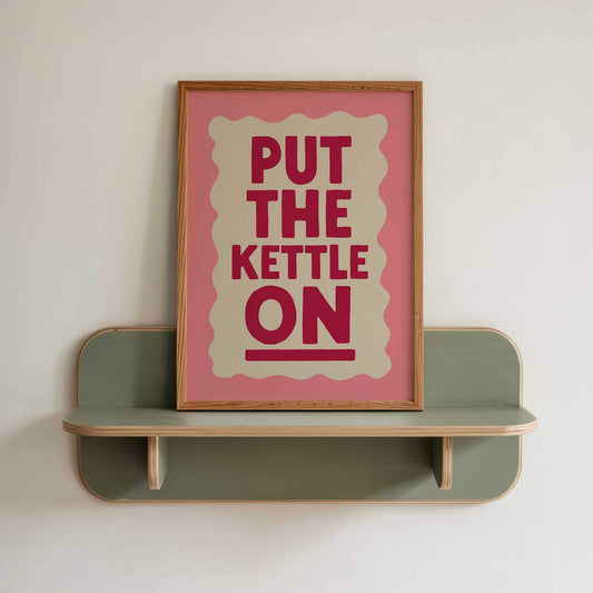 a pink framed poster with the text "PUT THE KETTLE ON" displayed on it.