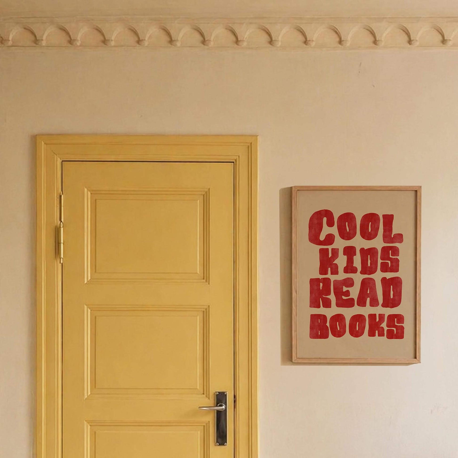 Yellow door with a framed poster reading 'Cool Kids Read Books' on a beige wall.