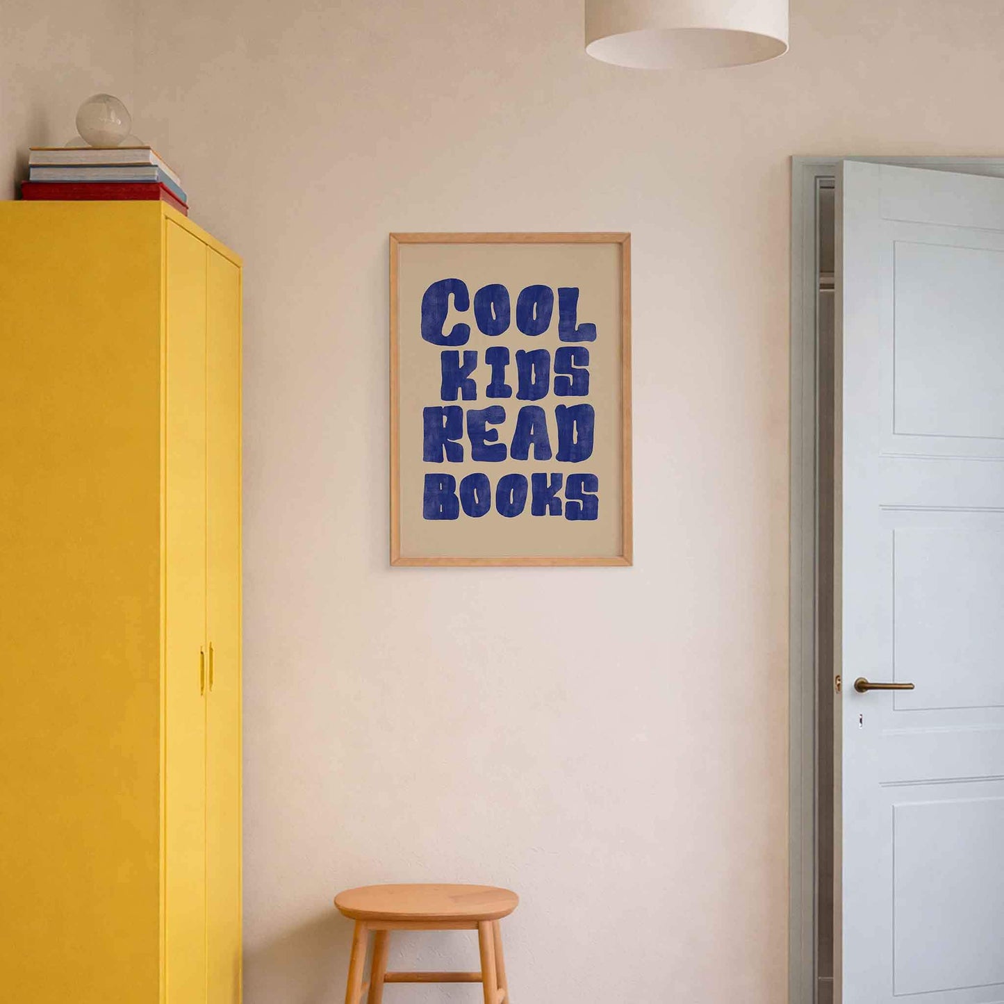 Room interior with a yellow cabinet, wooden stool, and framed poster on the wall.