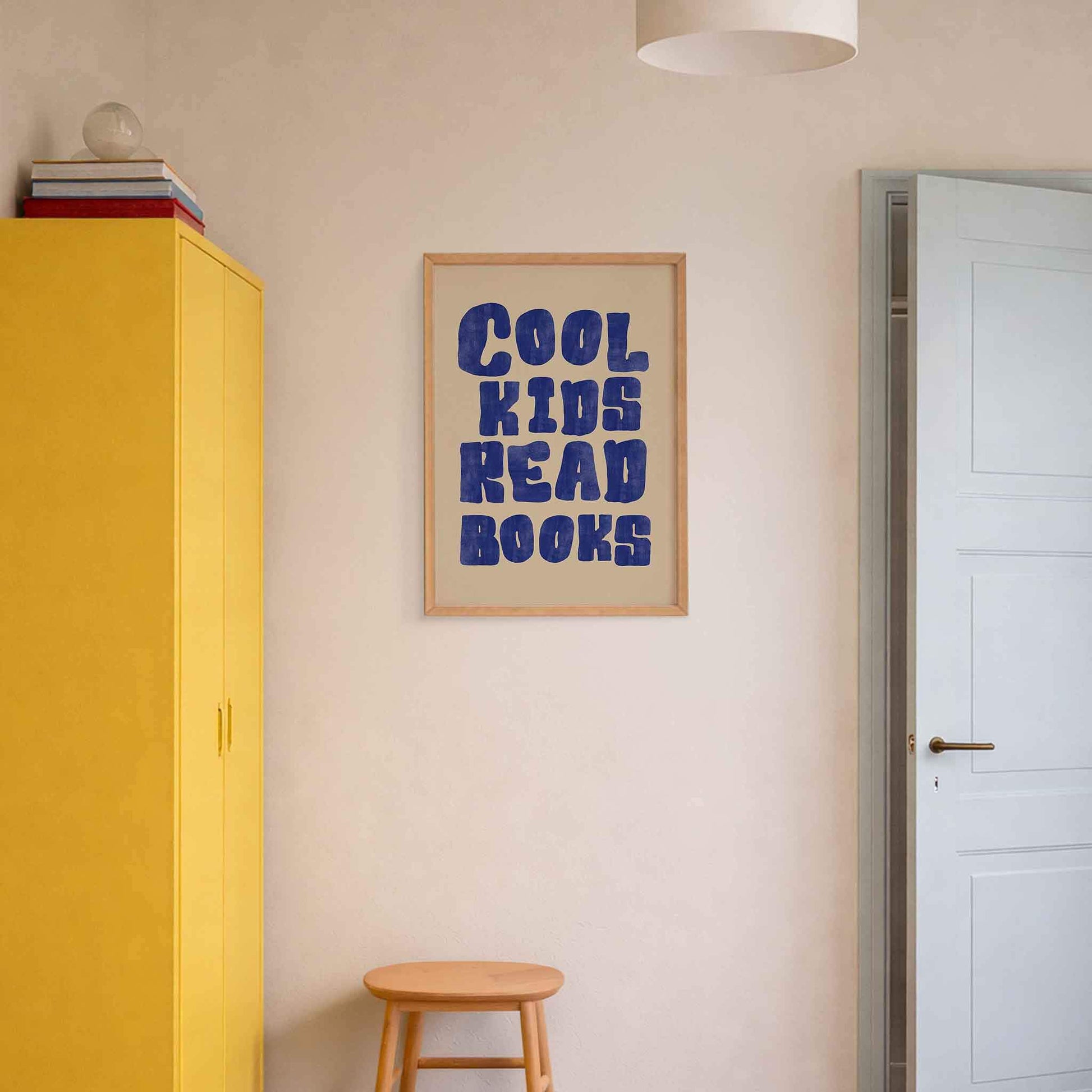 Room interior with a yellow cabinet, wooden stool, and framed poster on the wall.