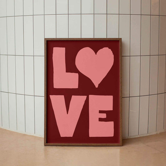 A framed image with the word "LOVE" written in large pink letters against a red background.