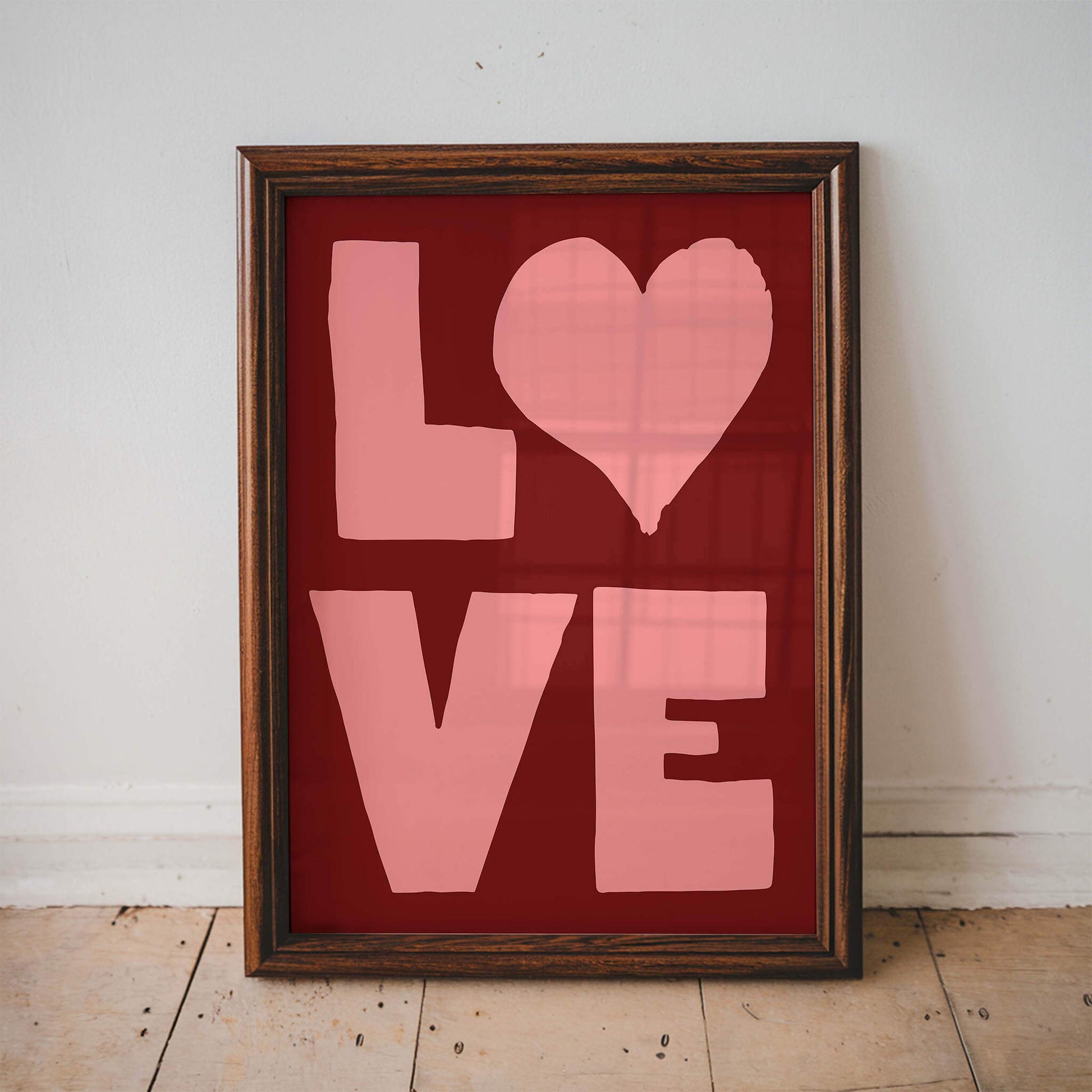 A framed image with the word "LOVE" written in large pink letters against a red background.