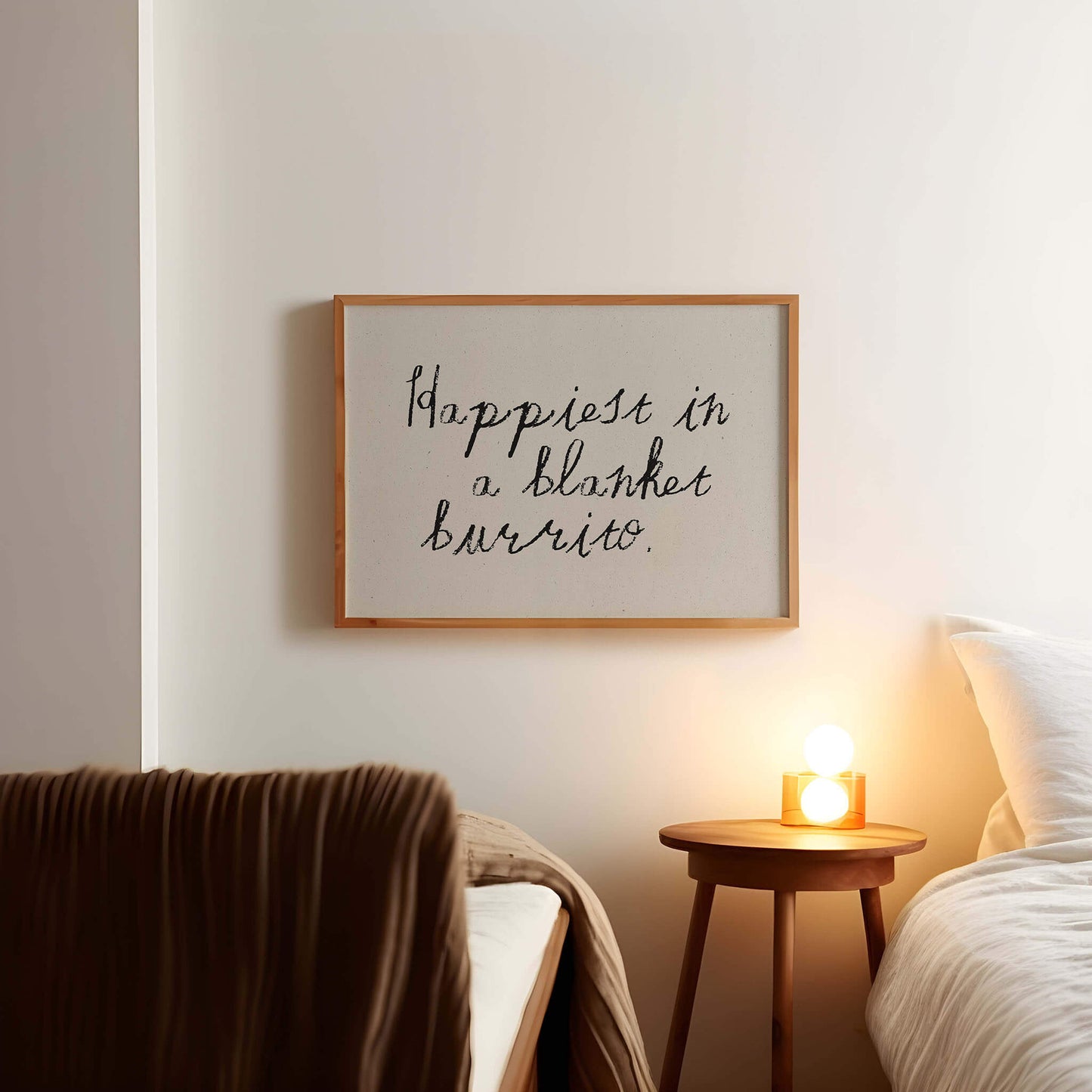 a bedroom setting with a framed quote on the wall that reads "happiest in a blanket burrito."