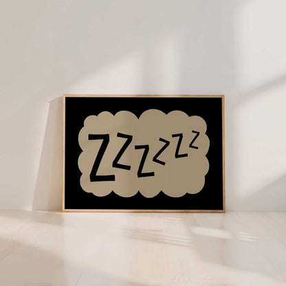 A framed poster with the word "zzzzzz" in a cloud-like shape, sitting on a wooden floor against a white wall.