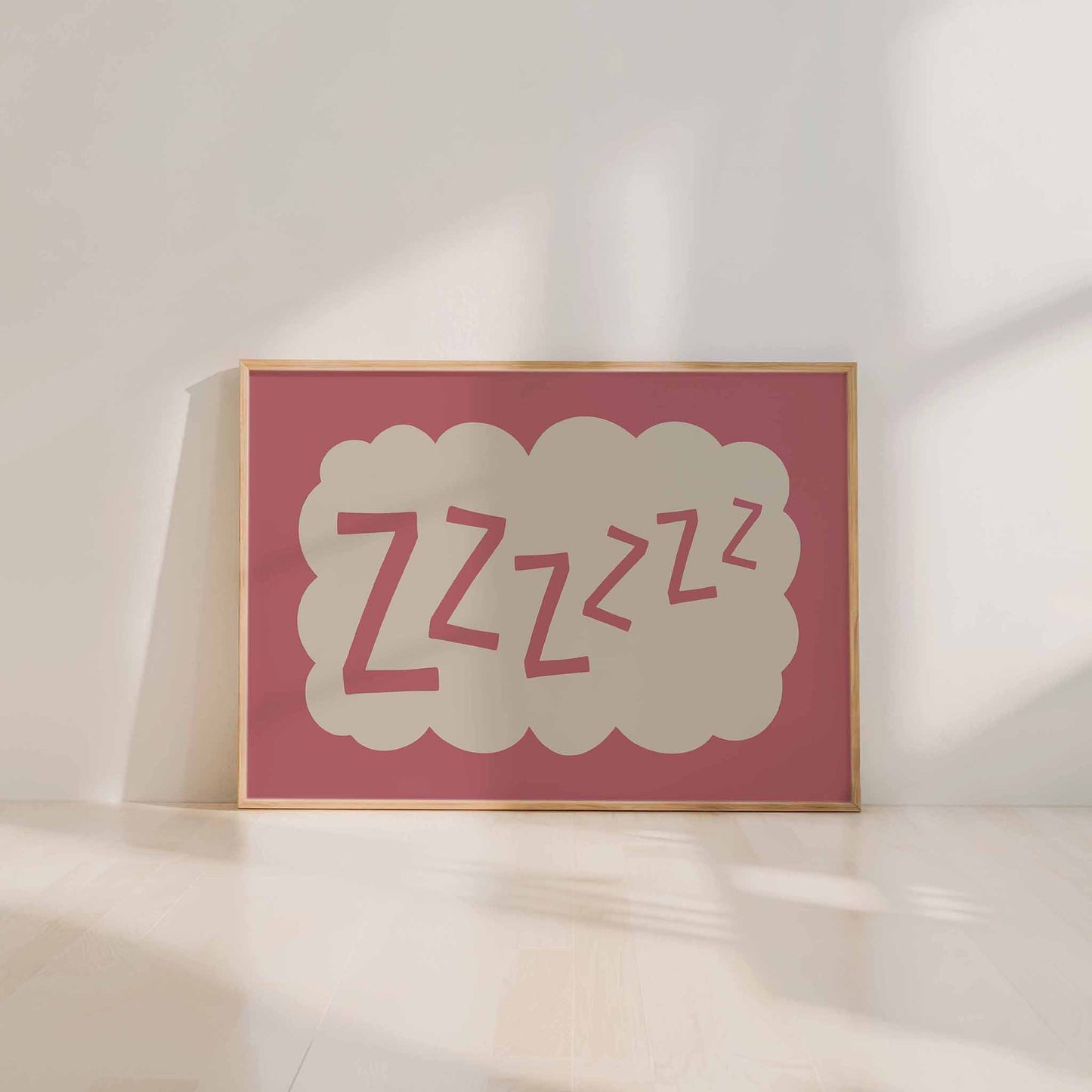 A framed poster with the word "zzzzzz" in a cloud-like shape, sitting on a white floor against a white wall.