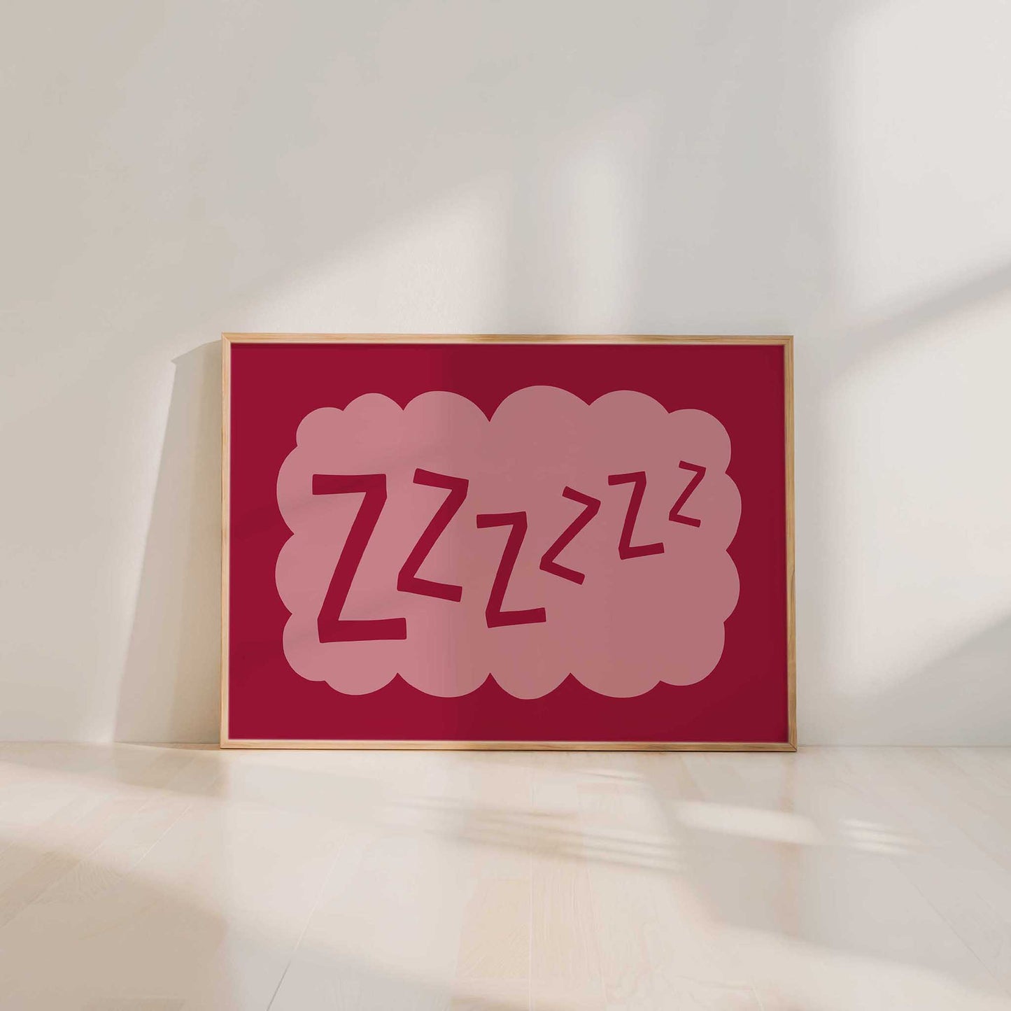A framed poster with a pink cloud-like design containing the text "zzzzzz" is displayed on a white wall.