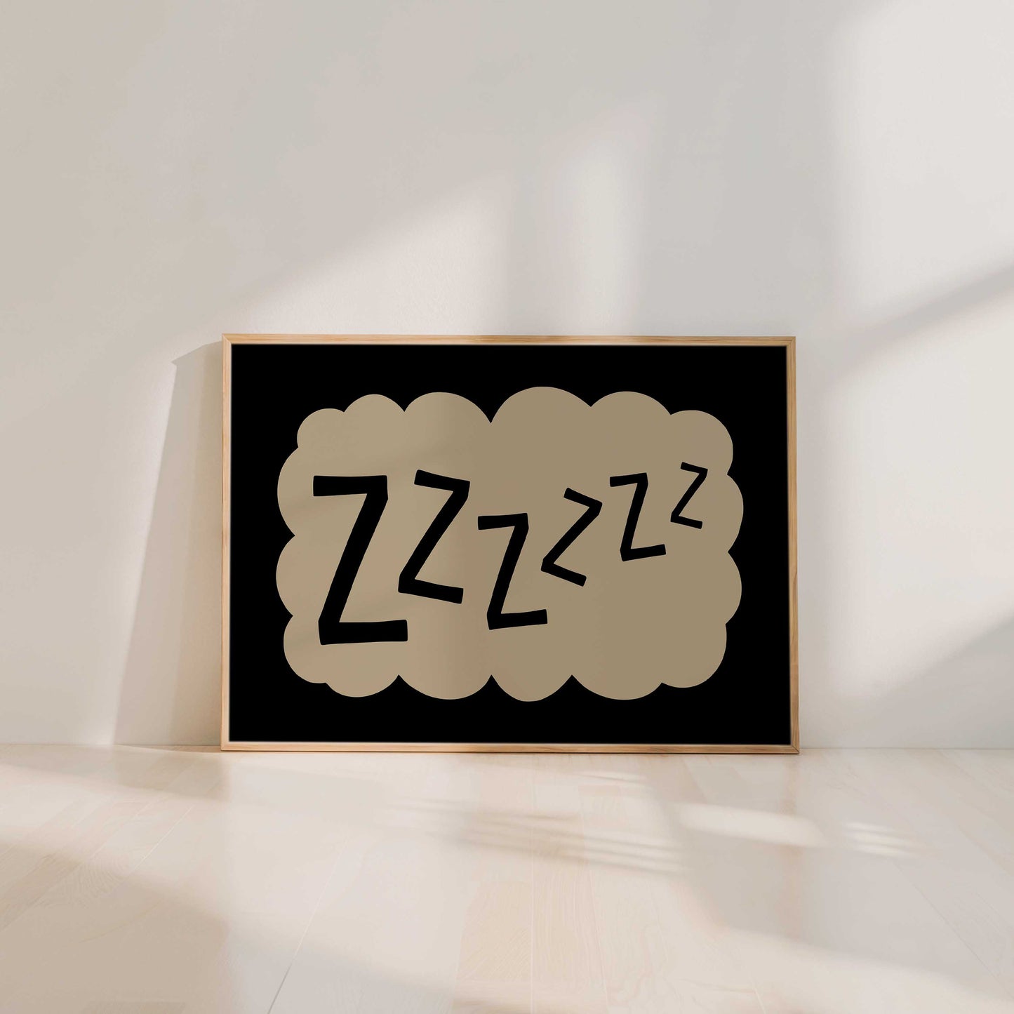 A framed poster with the word "zzzzzz" in a cloud-like shape, sitting on a wooden floor against a white wall.