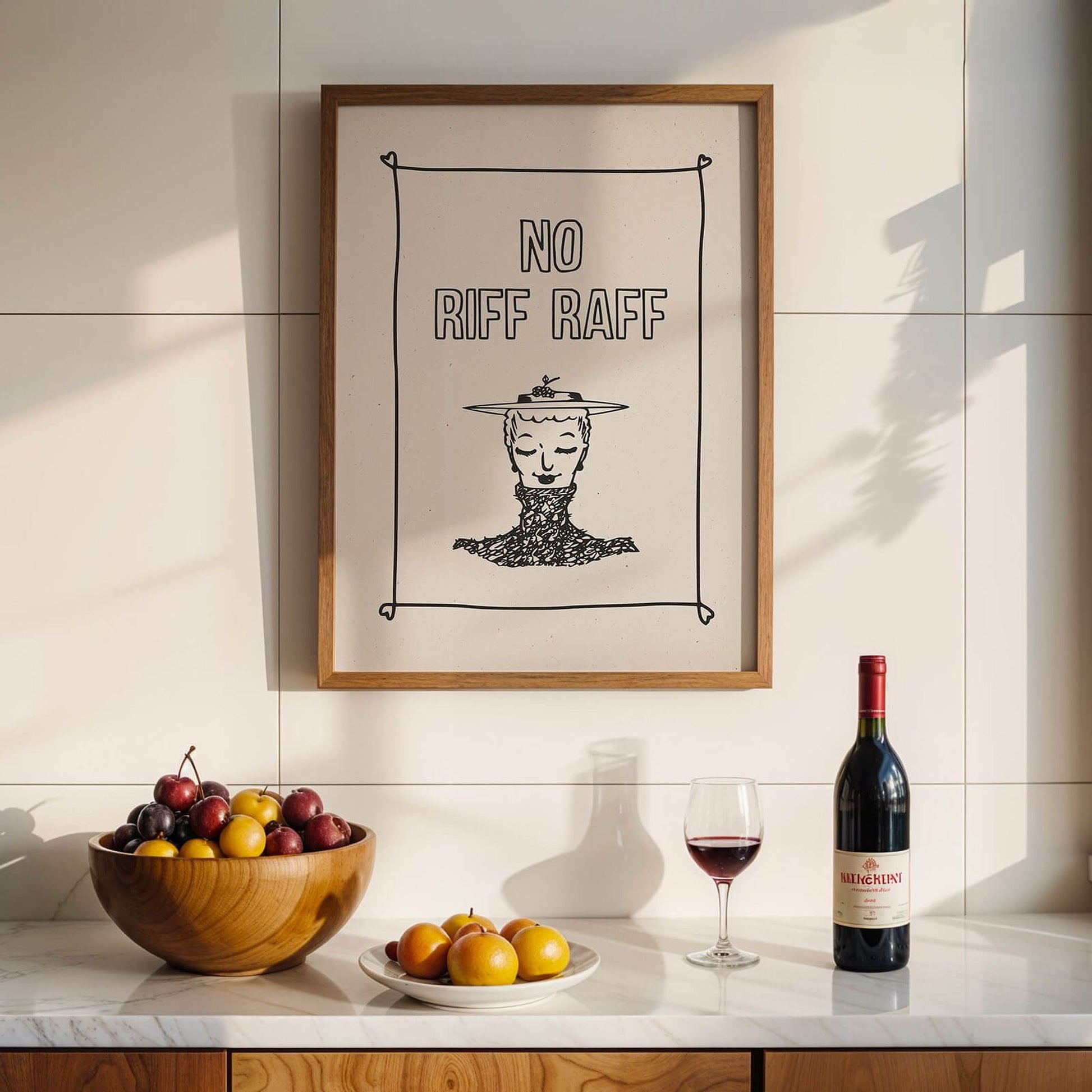 a framed poster with the text "NO RIFF RAFF" hanging on a wall above a wooden table with a bowl of fruit, a bottle of wine, and a glass of red wine.
